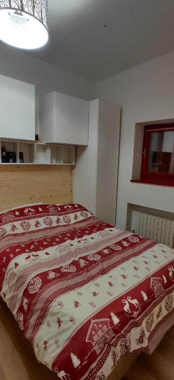 a bedroom with a bed with a red and white comforter at La casetta di Viola in Abetone