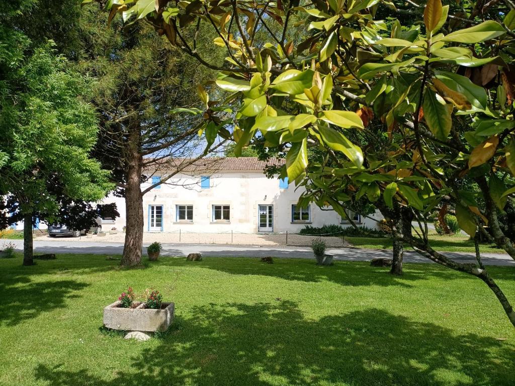 una casa en medio de un patio con árboles en Gîte de La Garenne, en Cozes