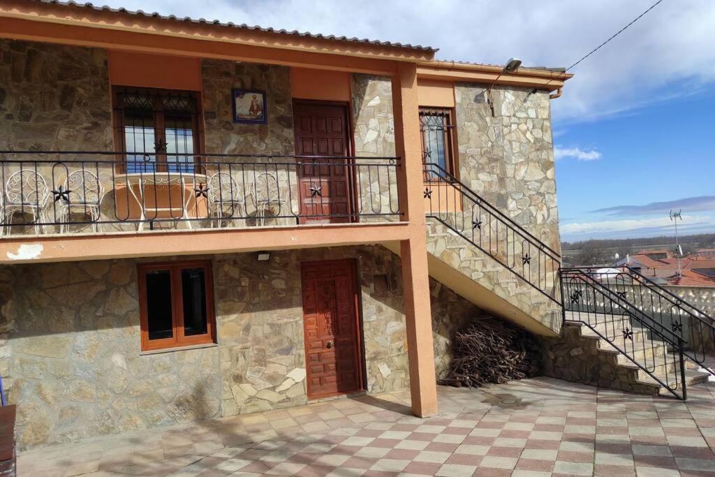 a stone house with a balcony and a staircase at Casa Rural La Vizana in Alija del Infantado