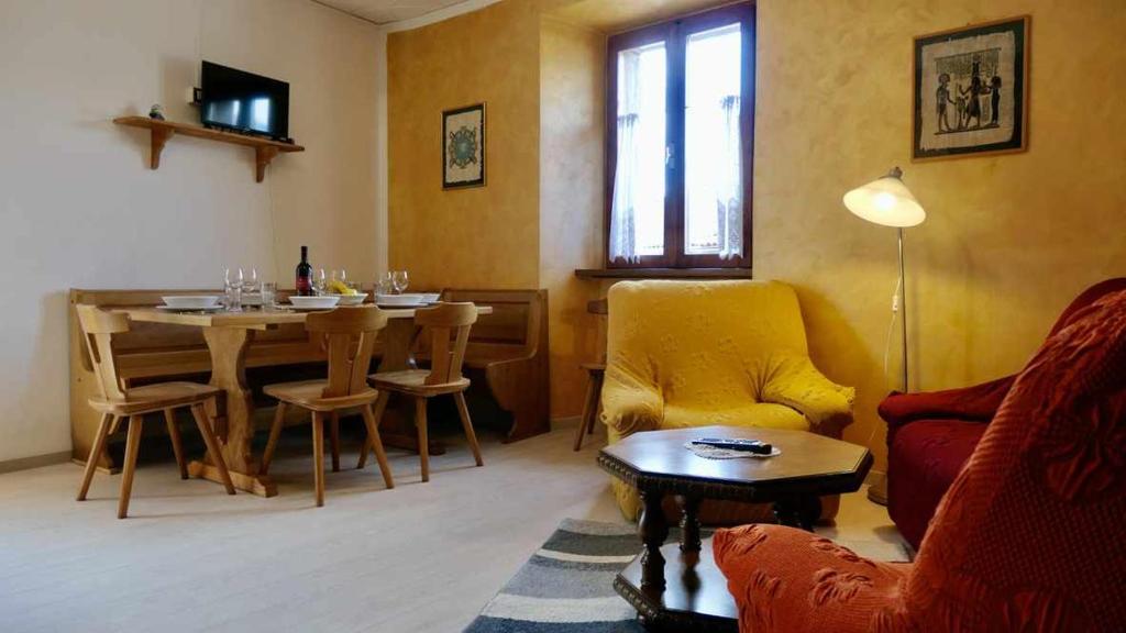 sala de estar con mesa y silla amarilla en Casa Malpaga Tenna Ospitar en Tenna 