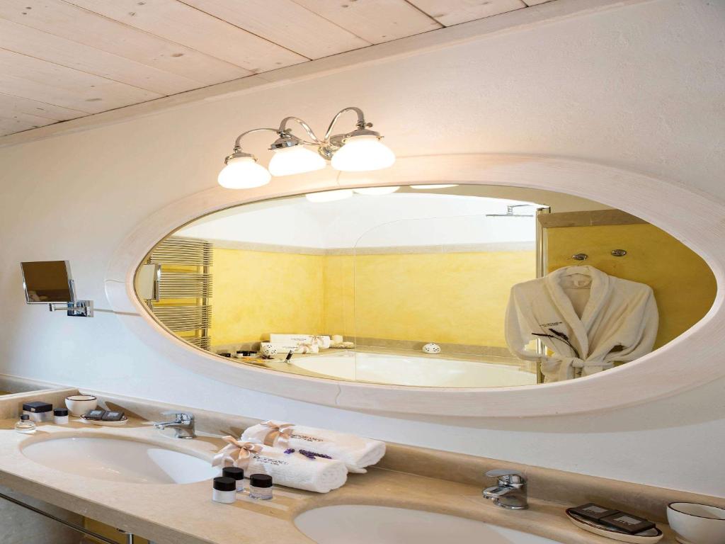 a bathroom with a sink and a large mirror at Borgobianco Resort & Spa Polignano - MGallery Collection in Polignano a Mare