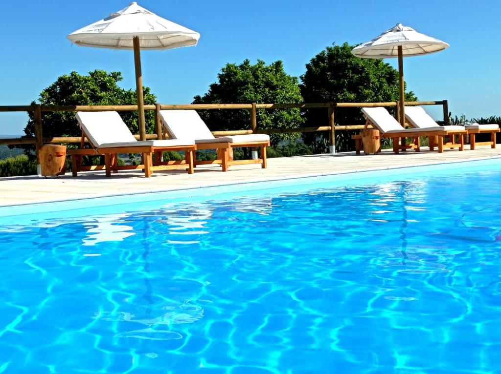 a swimming pool with chairs and umbrellas next to the water at Monte de Portugal in Montargil