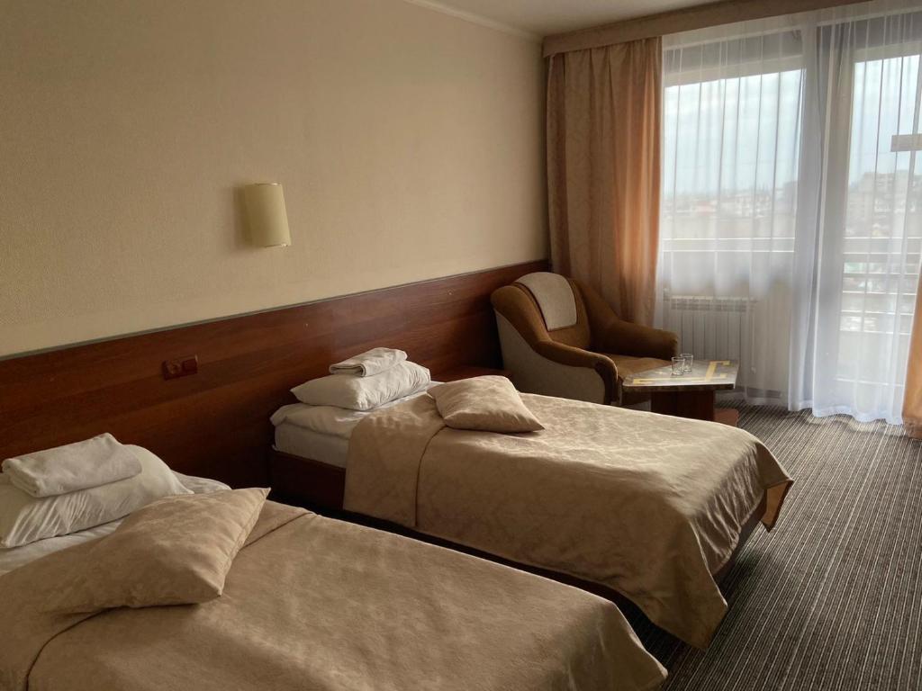 ウージュホロドにあるIntourist-Zakarpattia Hotelのベッド2台と窓が備わるホテルルームです。