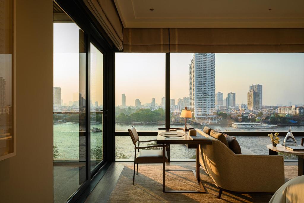 A compact desk and lounge chair set beside full-height windows overlooking the river and skyline.
