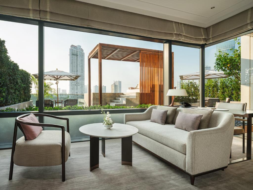 A bright sitting room with floor-to-ceiling windows, a sofa and river-facing outdoor terrace.