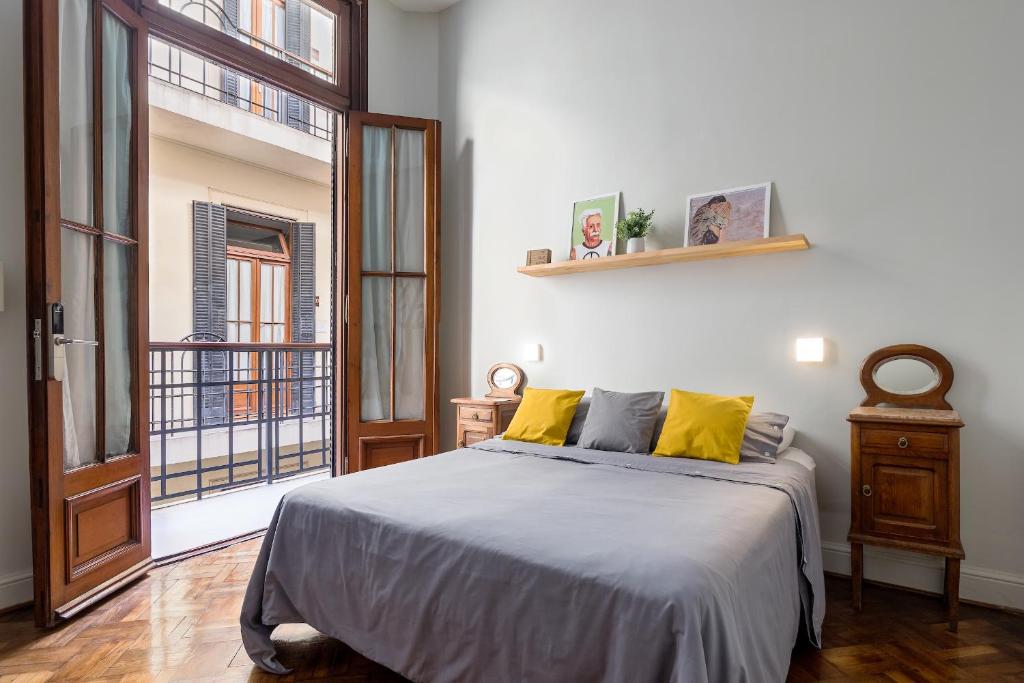 a bedroom with a bed with yellow pillows and a window at Milhouse Avenue in Buenos Aires