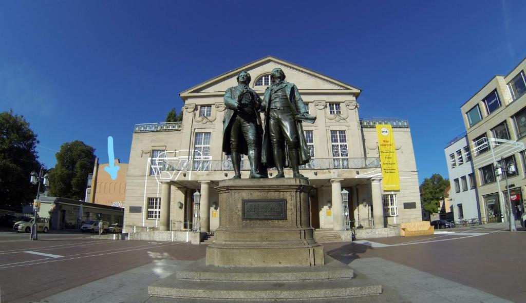 uma estátua de dois homens em frente a um edifício em Cityappartement am Theaterplatz em Weimar