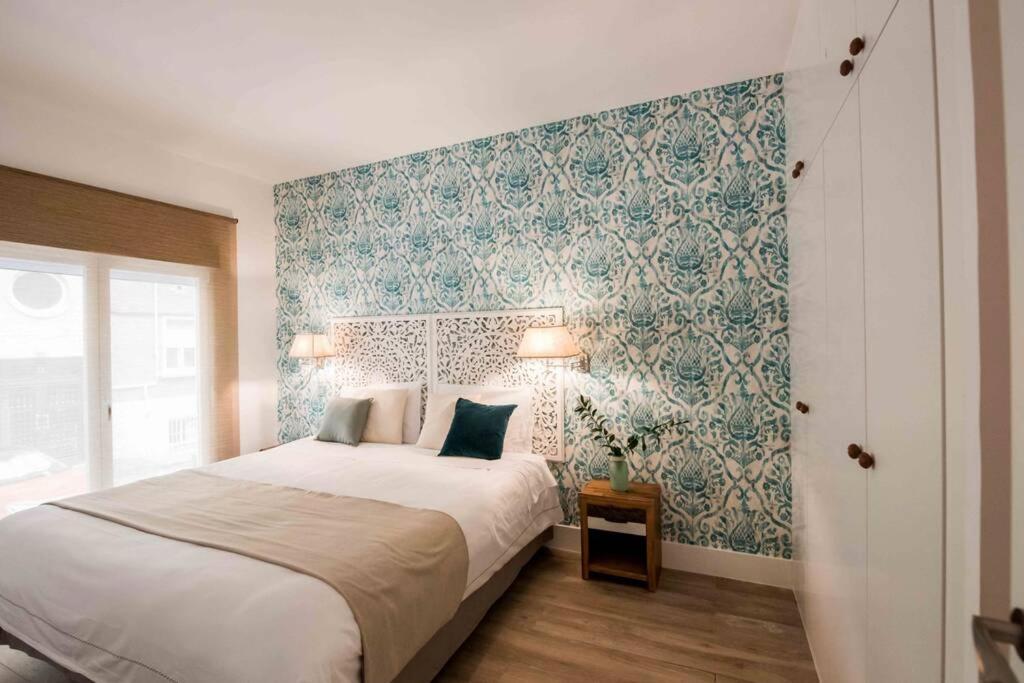 una camera da letto con un letto e carta da parati blu e bianca di HOMEABOUT GOYA Apartment II a Madrid