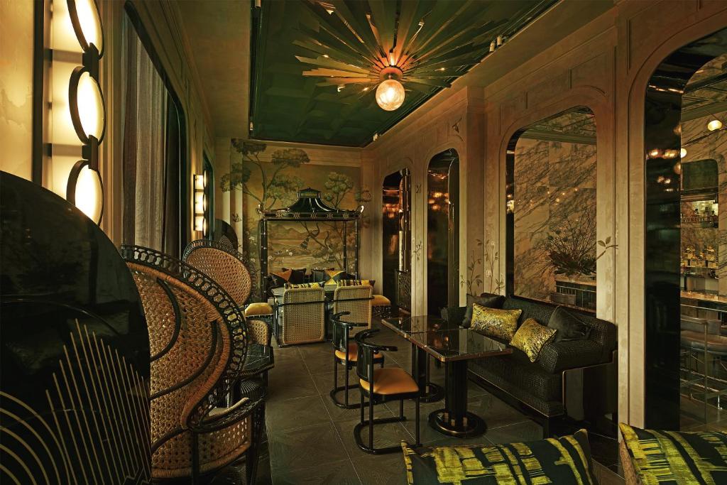A richly decorated interior lounge with rattan chairs, a sofa and small tables.