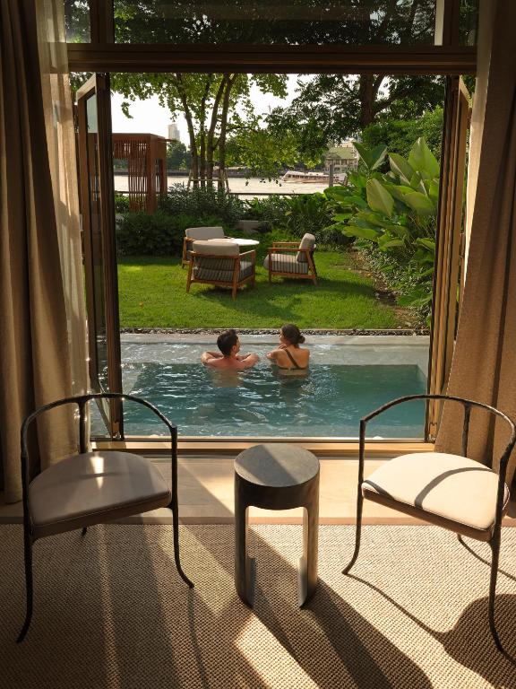 A private-looking plunge pool opens onto a garden with two loungers and greenery.