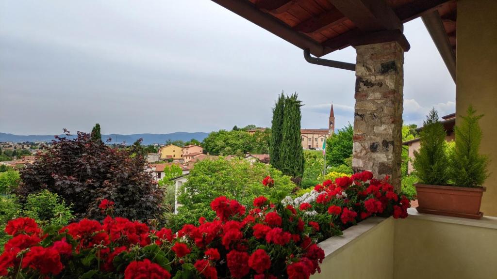 un jardín con flores rojas en un balcón en La Collina delle Acacie, en Grumolo Pedemonte