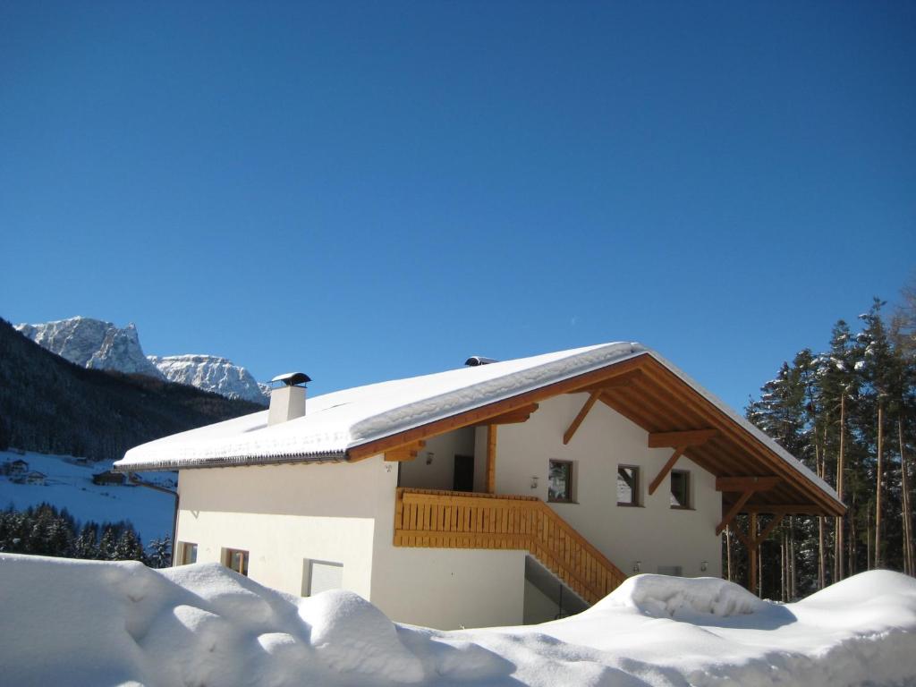 ein schneebedecktes Haus mit Bergen im Hintergrund in der Unterkunft Polzhof in Kastelruth