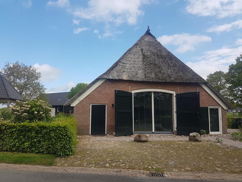 um pequeno edifício de tijolos com telhado de palha em Ermerhoek: op de Deel em Erm