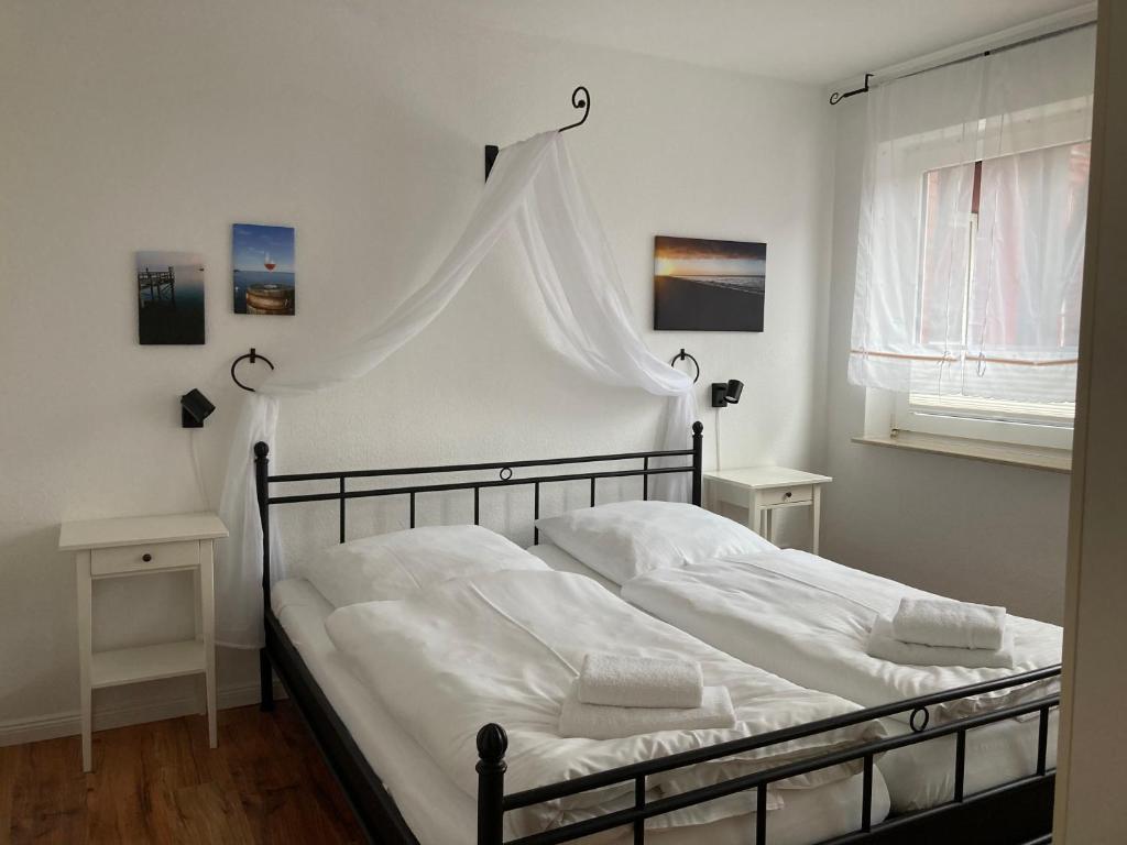 Schlafzimmer mit einem Bett mit weißer Bettwäsche und einem Fenster in der Unterkunft Hellinghaus FeWo 2 Klippenfänger in Wyk auf Föhr