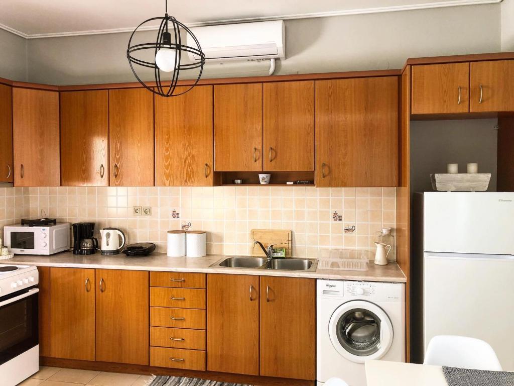 a kitchen with wooden cabinets and a washer and dryer at Helianthus Apartments in Argostoli