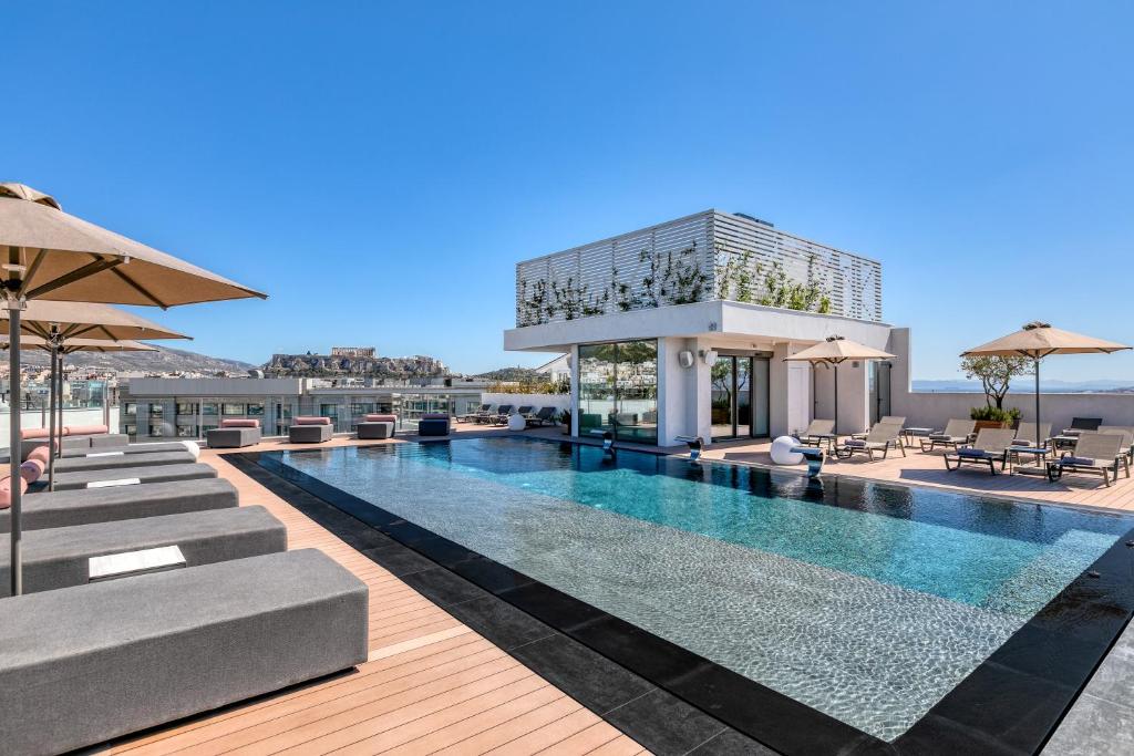 een zwembad met stoelen en parasols naast een gebouw bij The Stanley in Athene