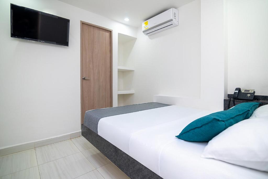 a bedroom with a bed with a television on the wall at Hotel Masinda in Cartagena de Indias