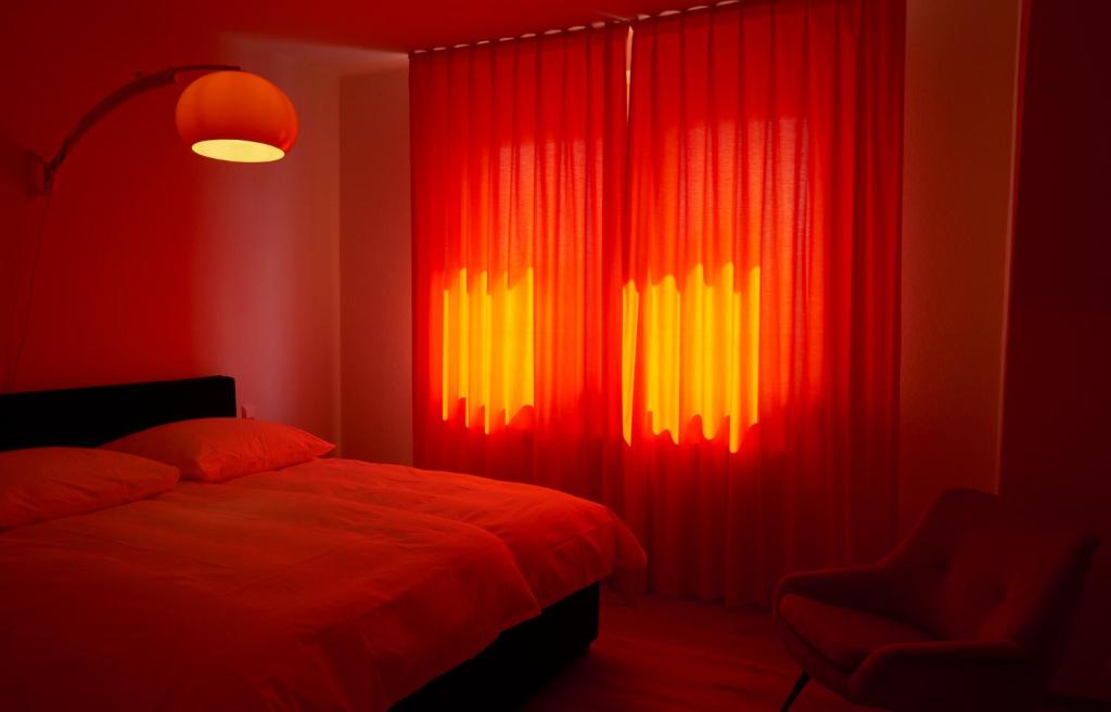 オッフェンブルクにあるホテル ウニオンの赤と黄色のカーテンとベッドが備わるベッドルーム1室