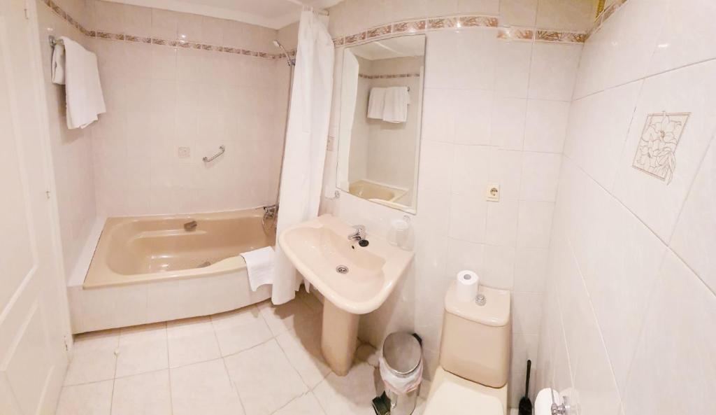 y baño con bañera, lavabo y aseo. en Apartamentos Pueblo Quinta, en Benalmádena