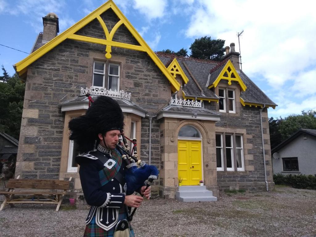 Un uomo in uniforme davanti a una casa di Ardvonie House a Kingussie