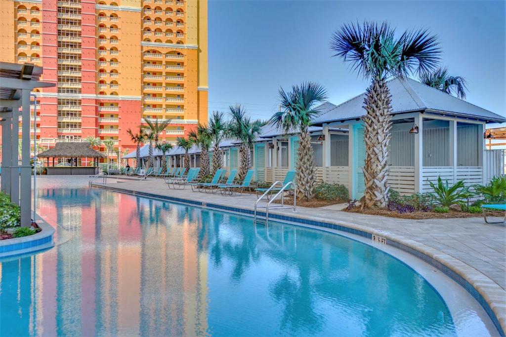 einen Pool in einem Resort mit Palmen und Gebäuden in der Unterkunft Tower 3 at Calypso Beach Resort in Panama City Beach