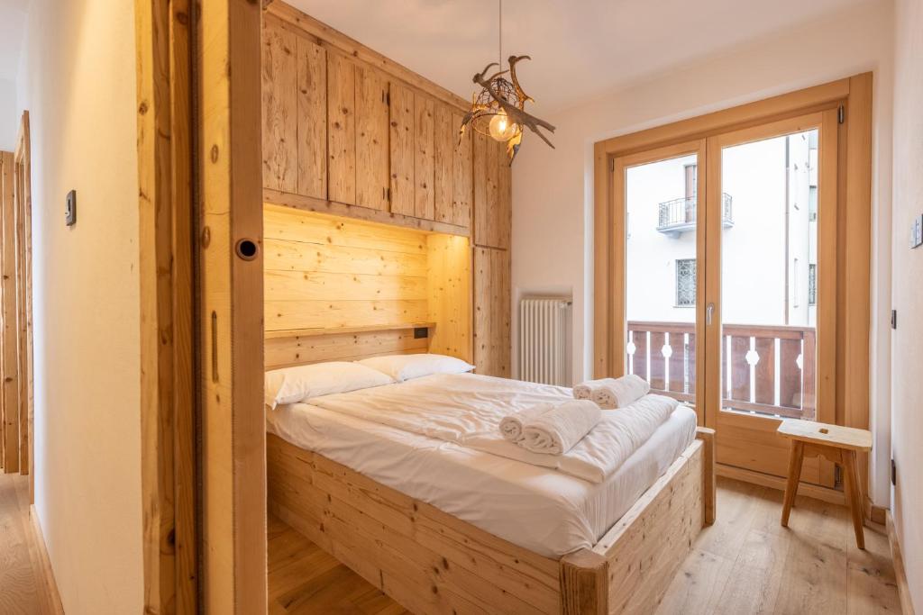 sypialnia z dużym łóżkiem i drewnianą ścianą w obiekcie Casa Olimpia w mieście Cortina dʼAmpezzo