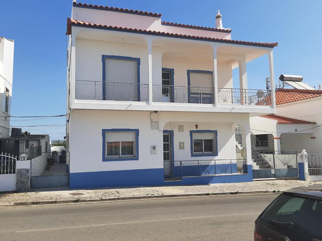a white and blue house with a balcony at Quartos para Ferias in Fuzeta