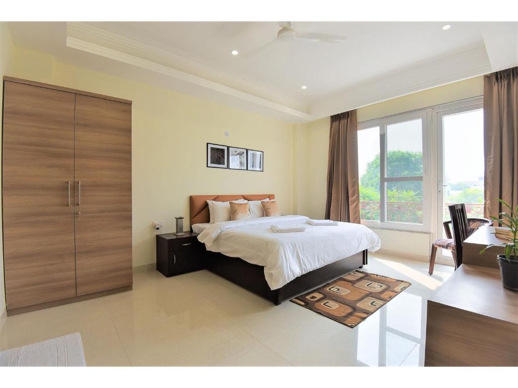 a bedroom with a bed and a large window at BluO Studio1 Golf Course Road, Gym, Balcony Garden in Gurgaon