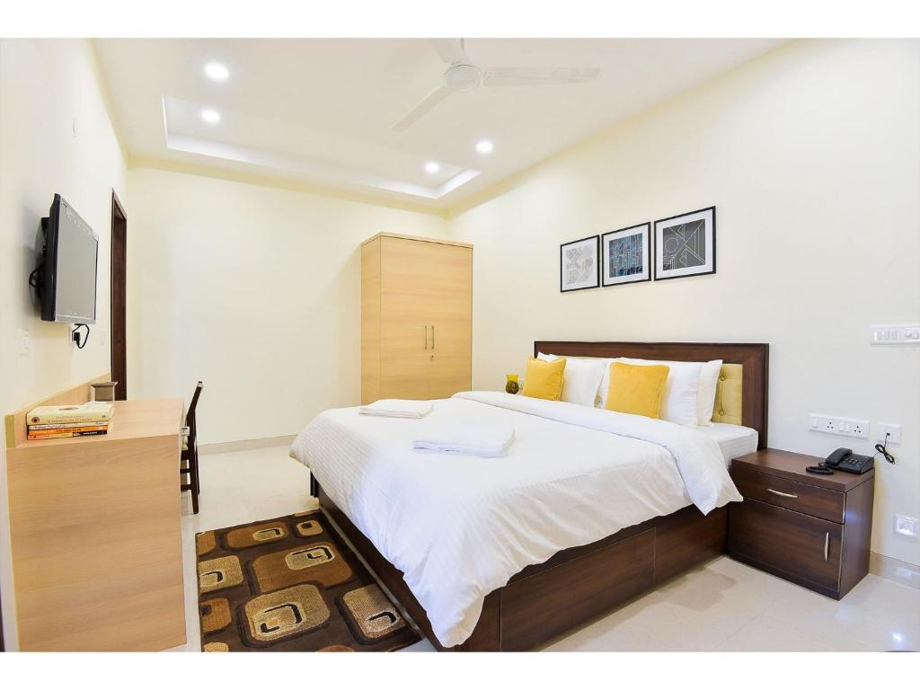 1 dormitorio con 1 cama grande y TV en BluO Studio5 Golf Course Road - Gym, Terrace Garden en Gurgaon