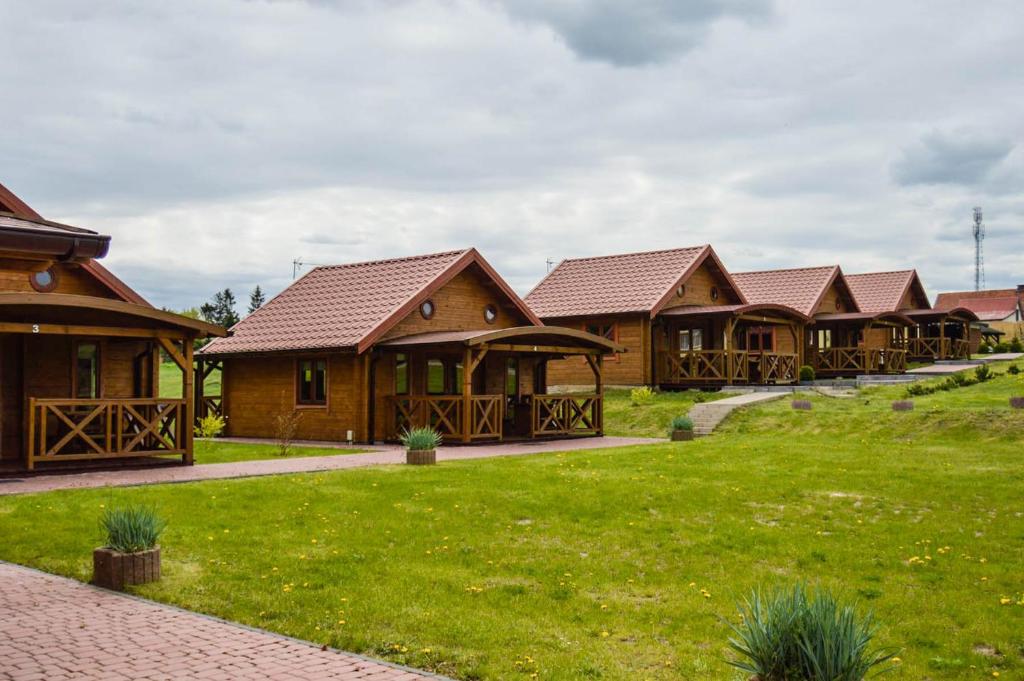 a row of wooden cottages with green grass at Gościniec Echo in Piecki