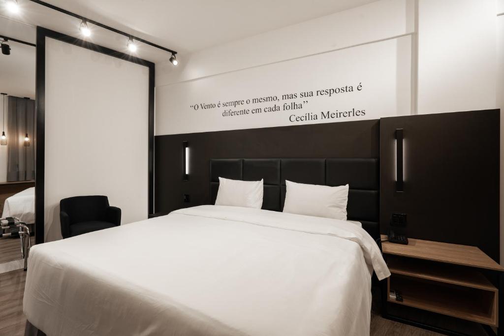 a bedroom with a large white bed and a sign at Slaviero Hotel Chapecó - Pet Friendly in Chapecó
