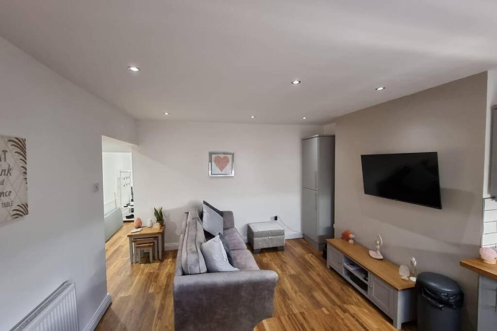 uma sala de estar com um sofá e uma televisão de ecrã plano em Crystal Cottage - 5 min walk from Holmfirth Town Centre em Holmfirth