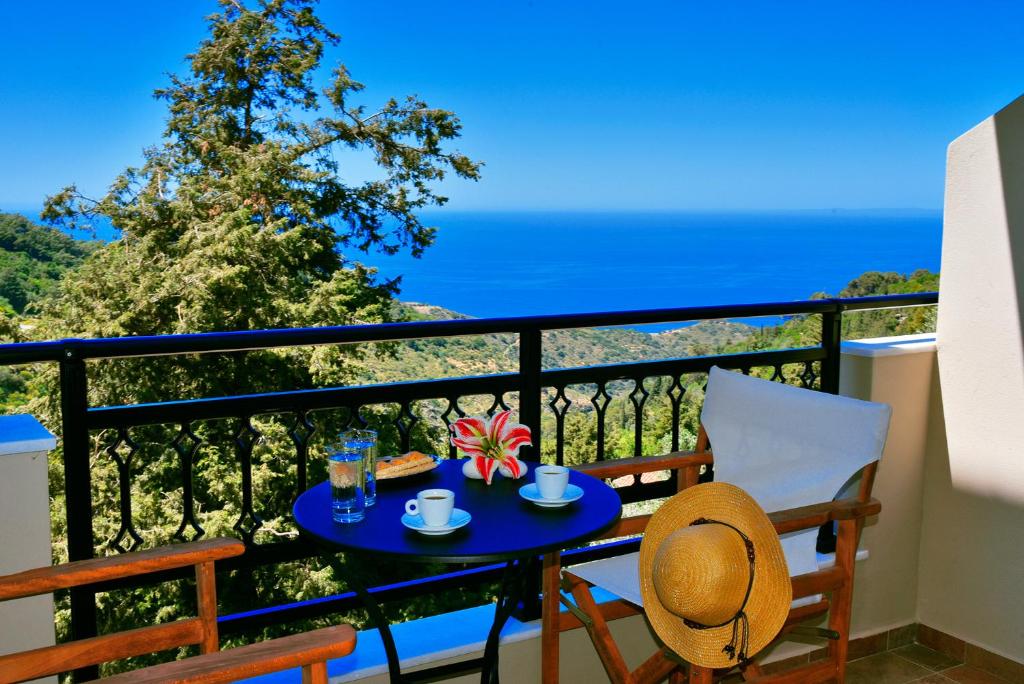 uma mesa e cadeiras numa varanda com vista para o oceano em House in Εndless green - Arethousa, Ikaria em Evdilos