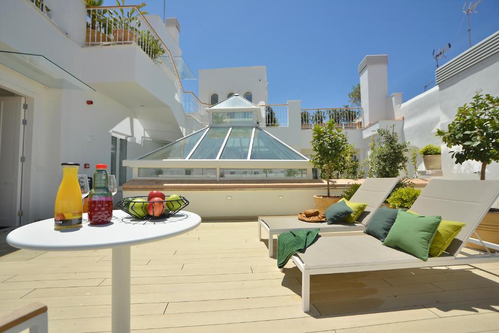 eine Terrasse mit 2 Stühlen, einem Tisch und einem Gebäude in der Unterkunft Plaza Mina Suites - Adults Recommended by Luxury Suites Cadiz in Cádiz