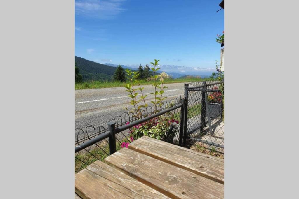 a wooden bench next to a fence on a road at Maison au sommet des montagnes in Boussenac