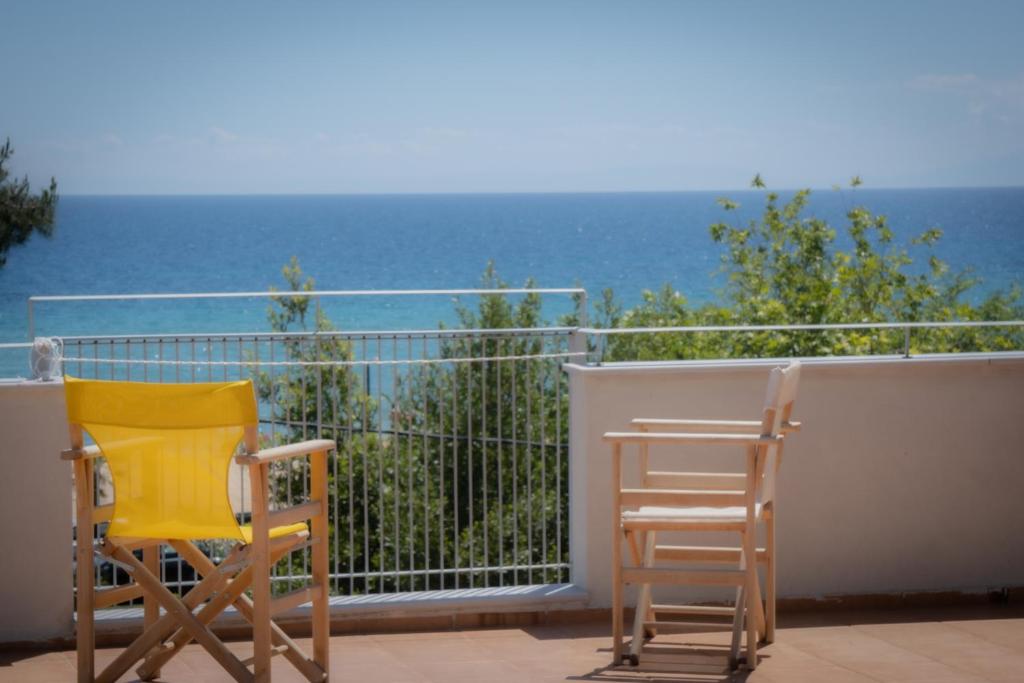 two chairs sitting on a balcony overlooking the ocean at ammos seafront family apartments in Nea Plagia
