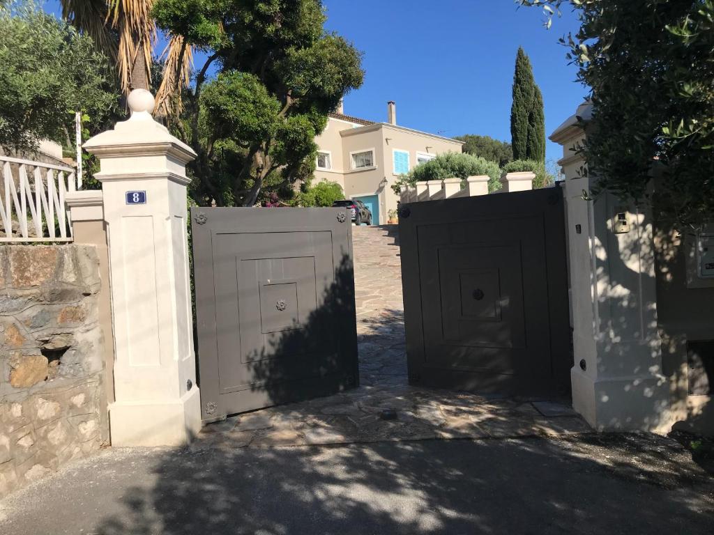 un portail dans une allée avec une maison en arrière-plan dans l'établissement Les Trèfles, à Hyères