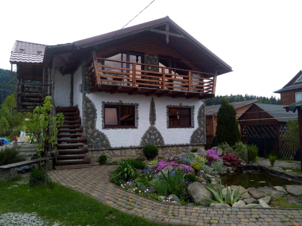 ein Haus mit einem Teich davor in der Unterkunft Апартаменти "У Кузьмича" 1 in Mykulytschyn