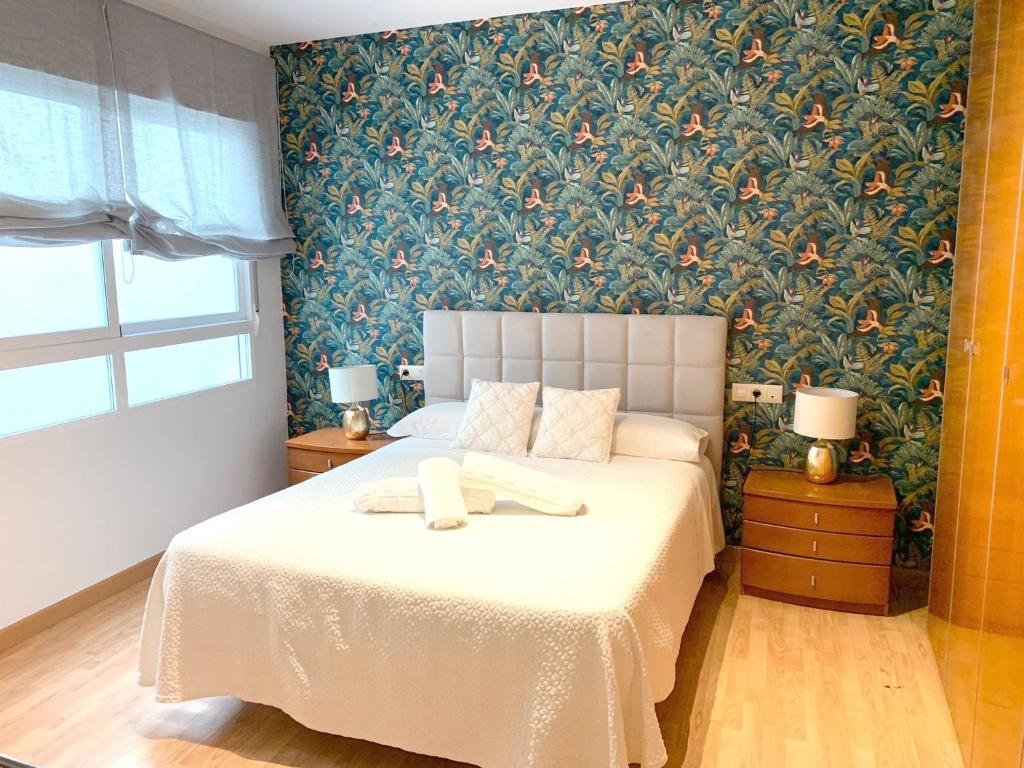 コルドバにあるTendillas Suiteの花柄の壁紙を用いた白いベッド付きのベッドルーム1室