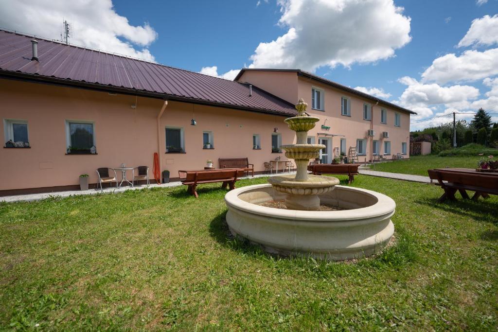 a fountain in the grass in front of a building at Pension V lukách in Dlouhá Ves