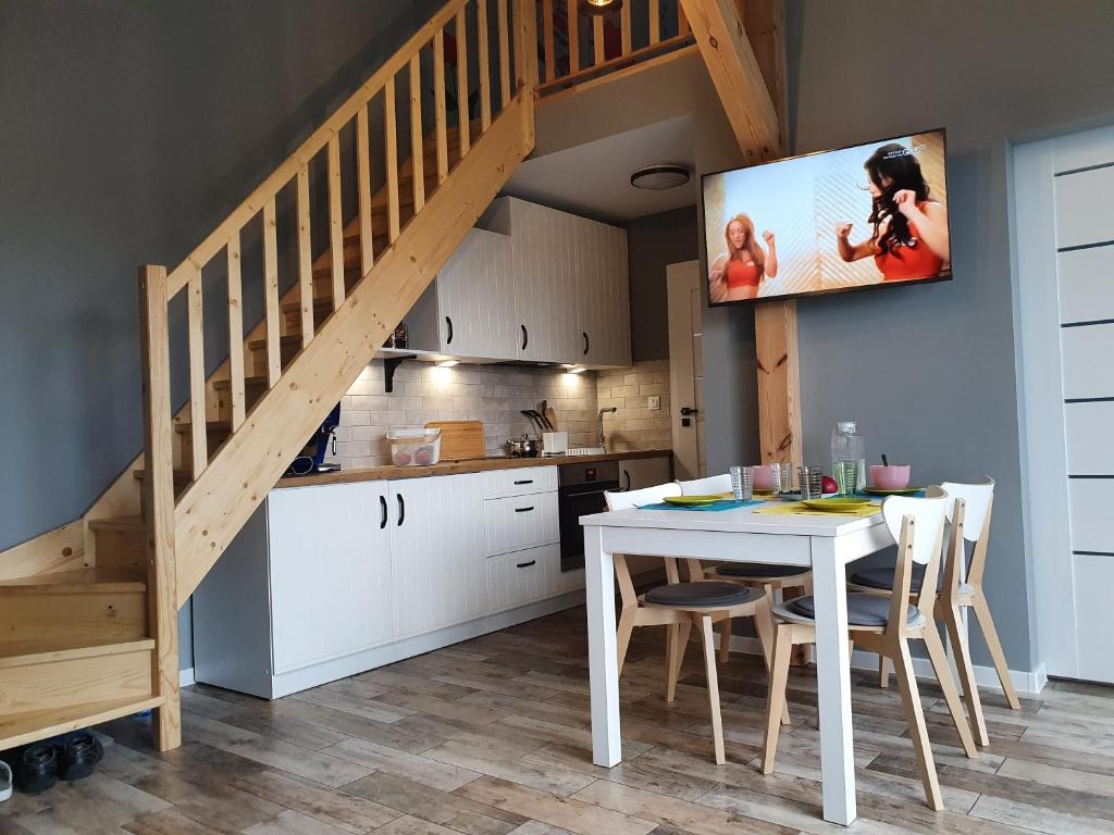 a kitchen with a white table with a tv on the wall at Willa Zacisze apartament 12 in Kąty Rybackie