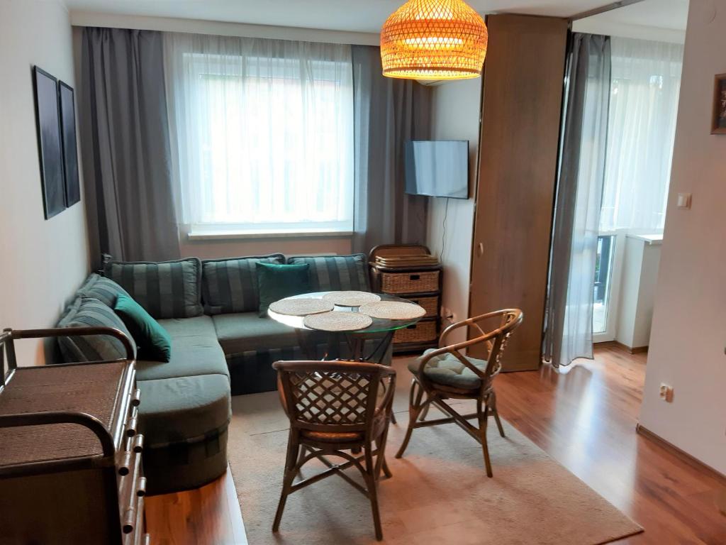 Una sala de estar con un sofá, una mesa y sillas. en Polanica Centrum, en Polanica-Zdrój