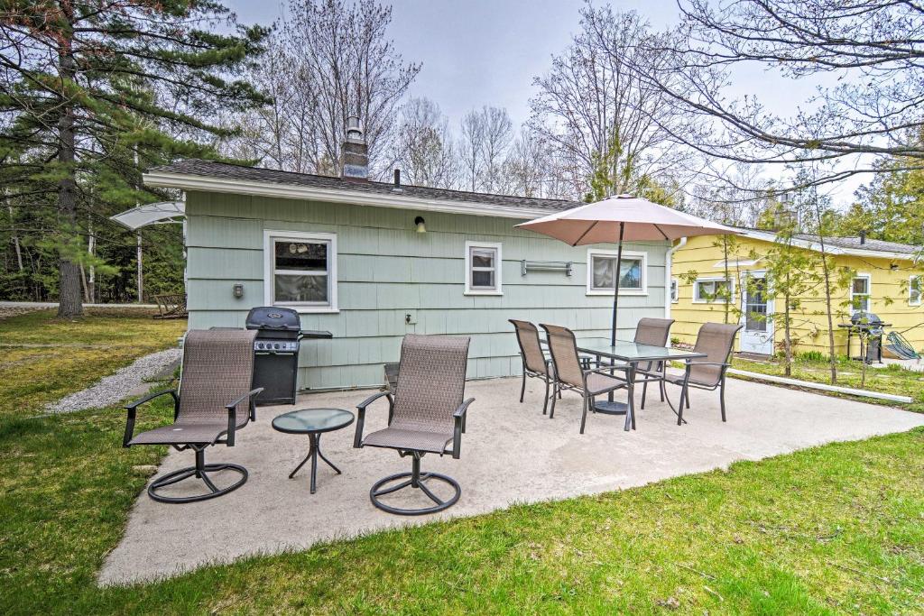 un patio con sillas y una mesa con sombrilla en Charlevoix Cabin with Patio and Grill - Steps to Lake! en Charlevoix