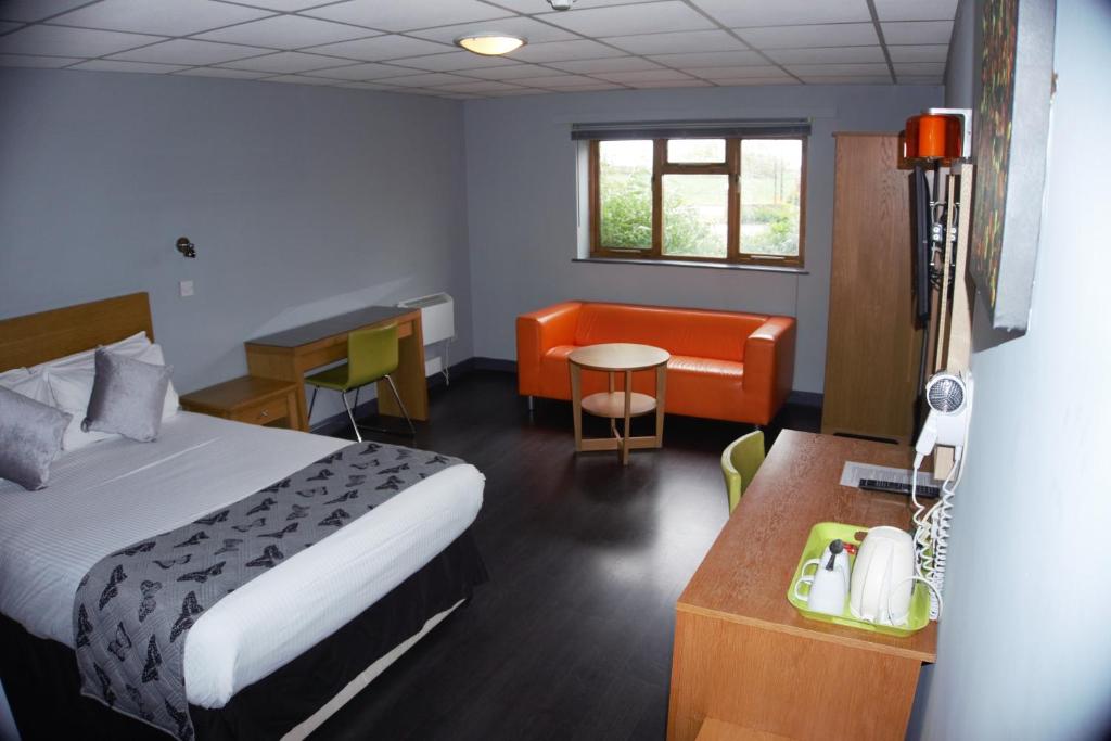 a hotel room with a bed and a desk and chair at Happy Guests Lodge in Lower Whitley