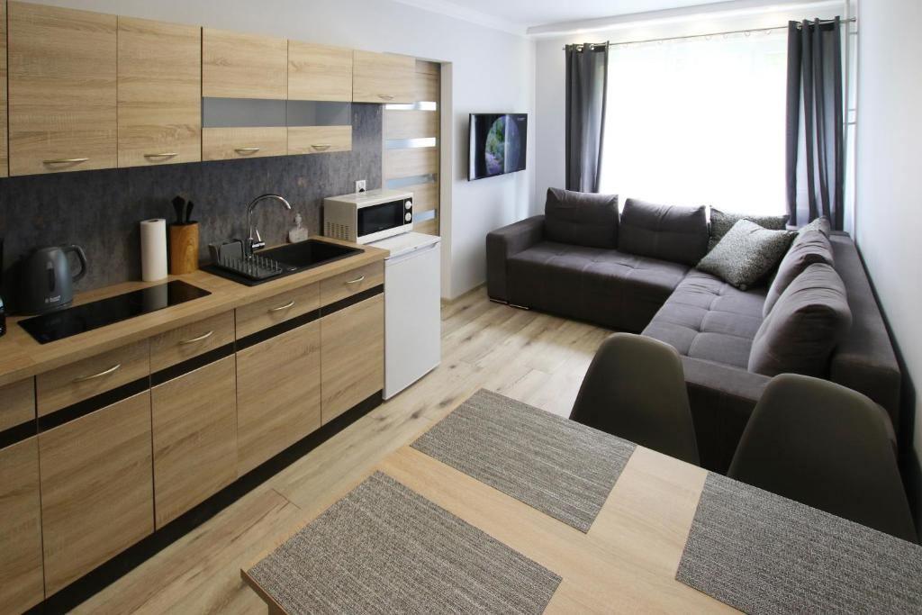 a kitchen and a living room with a couch at Apartament Navigare in Kołobrzeg