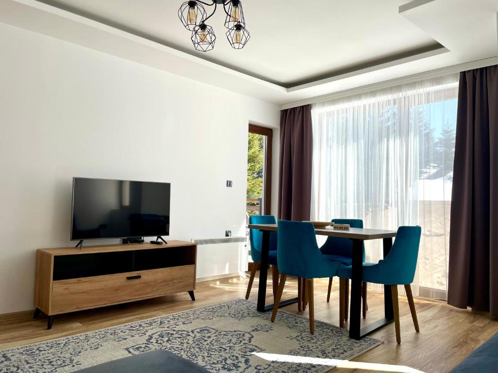 Zlatna Kruna - Lux Apartments Kopaonik في كوباونيك: غرفة معيشة مع طاولة طعام وتلفزيون