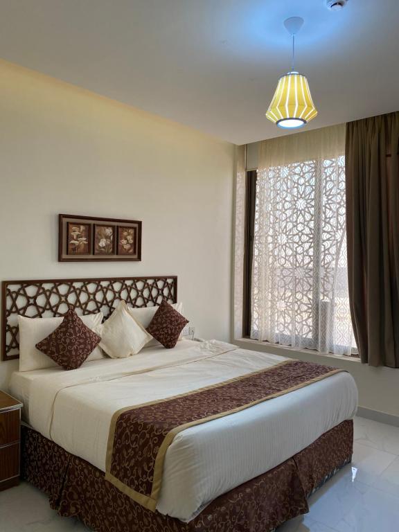 a bedroom with a large bed with a large window at سوار الذهب للشقق المخدومة in Sīdī Ḩamzah