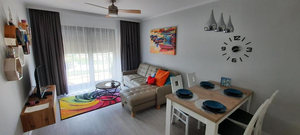 sala de estar con mesa, sofá y reloj en GARDENIA Apartament Przy Plaży 19, en Dziwnów