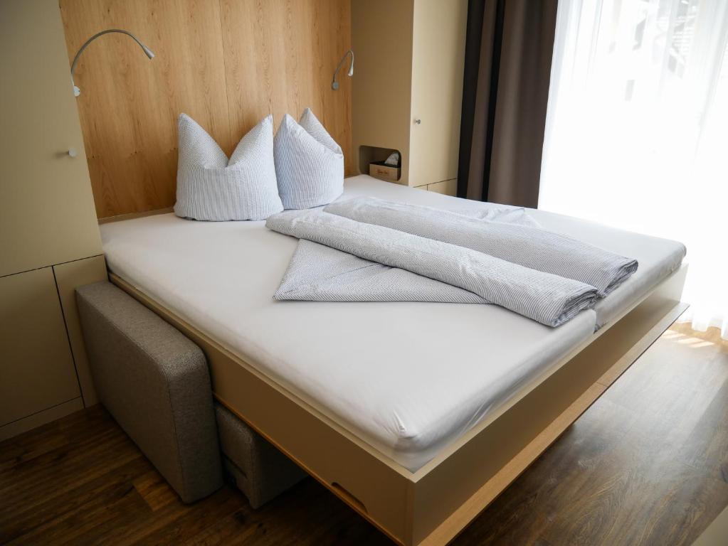 uma cama com lençóis brancos e almofadas em 5Rooms Frühstückspension em Sankt Stefan im Rosental