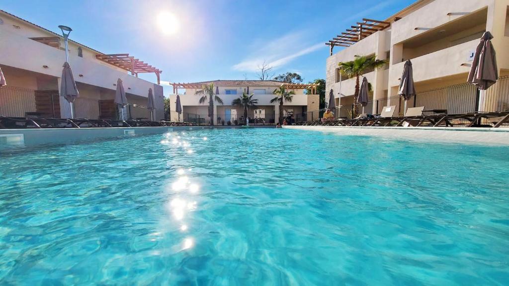 - une piscine d'eau bleue dans un hôtel dans l'établissement MARINE DE BRAVONE T2 Terrasse Front de mer - Plage pieds dans l'eau - Clim - Piscine - WIFI, à Linguizzetta